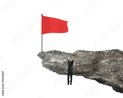 Businessman hanging on cliff with red wavy flag on top photo