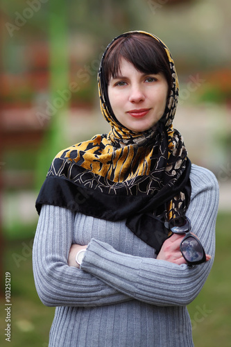 Portrait of young woman in park with a scarf on a head