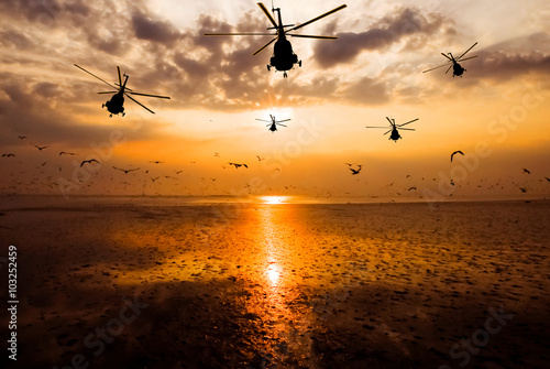 Silhouette of the military helicopter  moving into sky at sunset