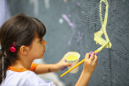 Young girl paints the  wall