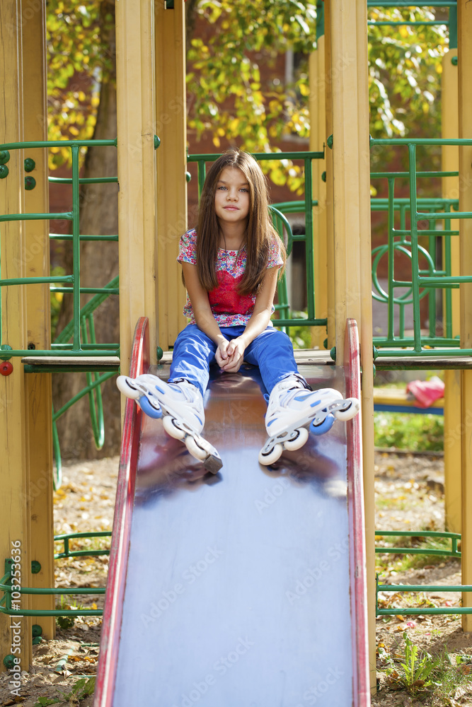 Little girl sitting at the playground in roller skates