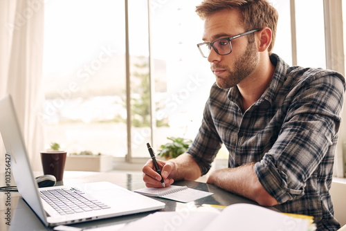 young adult writer looking at his notebook screen