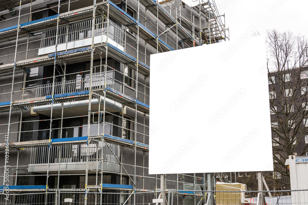 Leeres Schild vor Baustelle mit eingerüstetem Haus Leeres Schild vor Baustelle mit eingerüstetem Haus