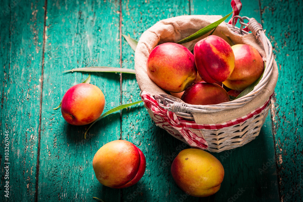 Fresh peaches in a basket on rustic wooden table. Fresh peaches in a basket on rustic wooden table.