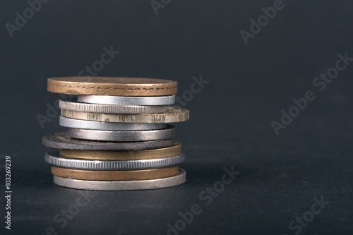 stack of old coins on black background, closeup.