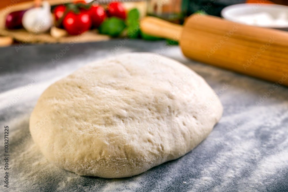 Rolling pizza dough with wooden roller Rolling pizza dough with wooden roller