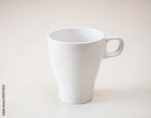 White cup on light wooden table. Horizontal format.