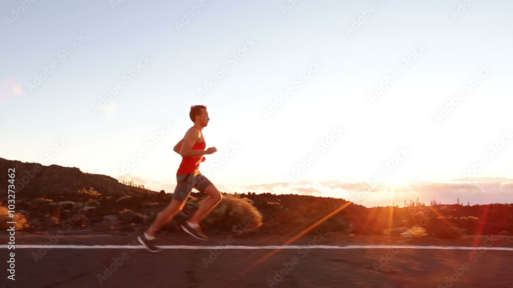 Running runner man athlete training outdoors exercising on mountain road at sunset in amazing landscape nature. Fit handsome athletic male working out for marathon run outside in summer.