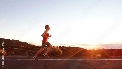 Running runner man athlete training outdoors exercising on mountain road at sunset in amazing landscape nature. Fit handsome athletic male working out for marathon run outside in summer.
