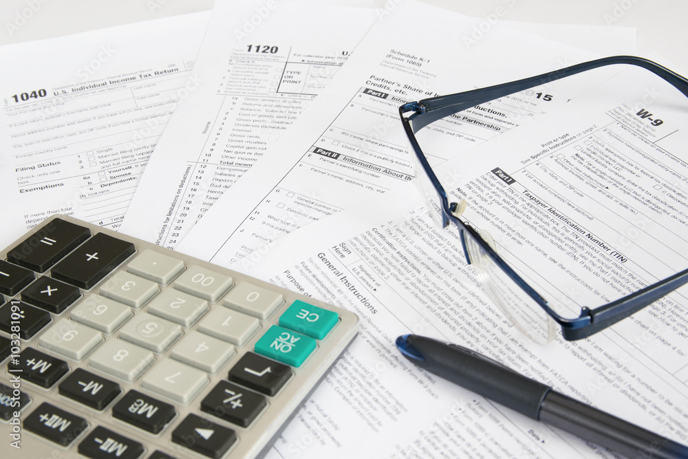 US tax forms with calculator, glasses and pen. US tax forms with calculator, glasses and pen.
