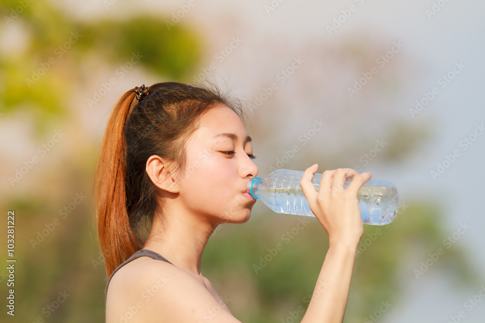 Sporty woman asia drinking water outdoor on sunny day