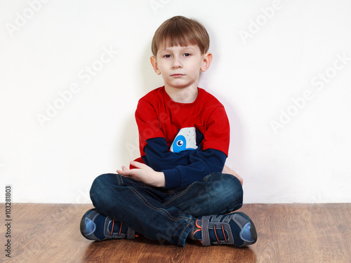  sad boy sitting near the wall