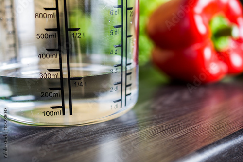 250ccm / 1/4 Liter / 250ml Of Water In A Measuring Cup On A Kitchen Counter With Food photo