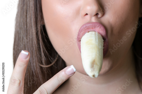 Closeup picture of woman eating ripe banana, making a peace symbol with her fingers
