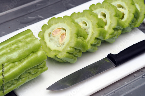 Fresh green bitter melon or bitter gourd on chopping board with knife