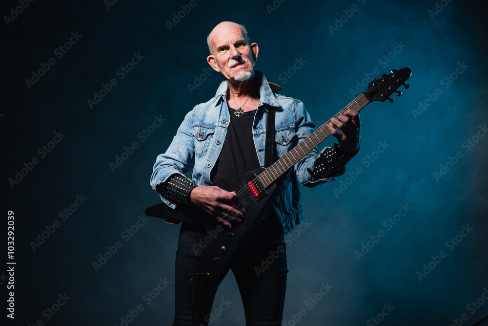 Fototapeta premium Bald heavy metal senior man with electric flying-v guitar in fro