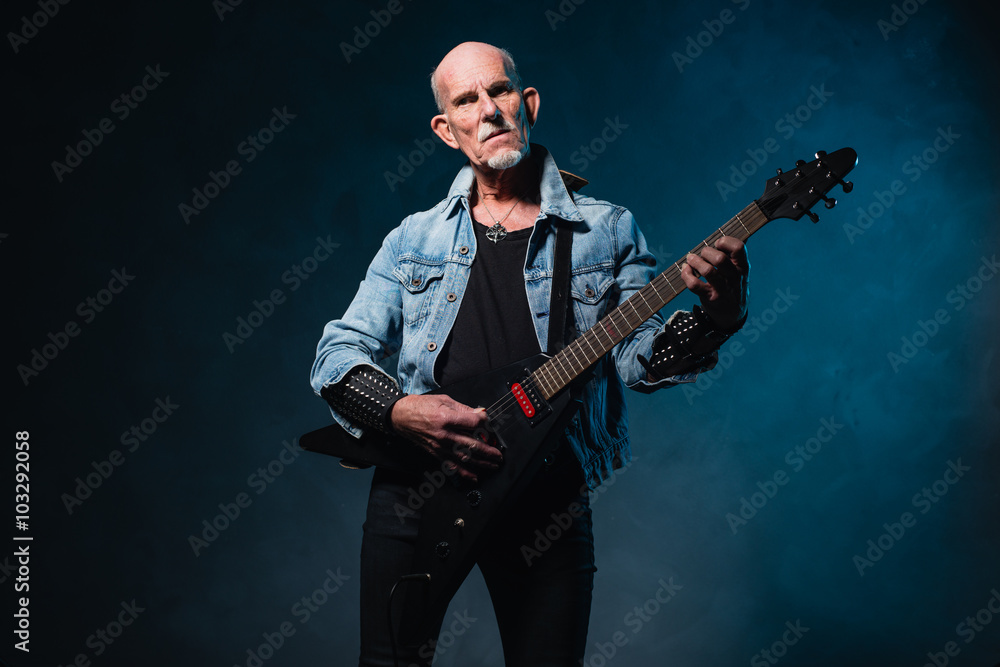Bald heavy metal senior man with electric flying-v guitar in fro
