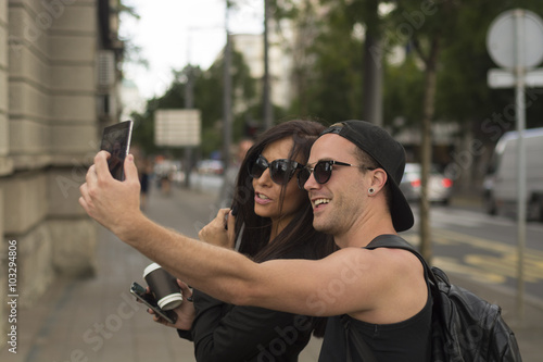 Cheerful friends taking photos of themselves on smart phone