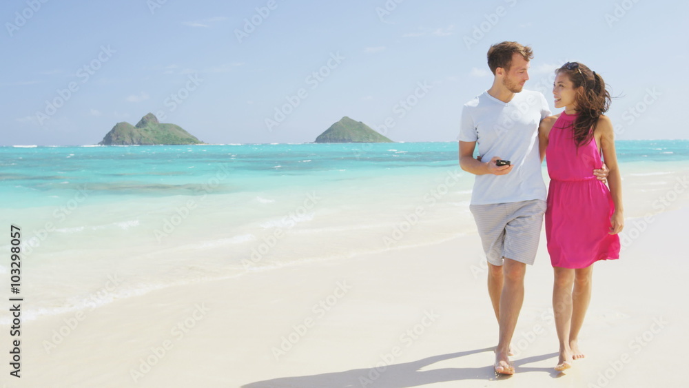 Couple walking on beach vacation using smart phone app. Romantic couple in love on honeymoon having fun on Lanikai beach, Oahu, Hawaii. Couple holding smartphone. RED EPIC SLOW MOTION. Couple walking on beach vacation using smart phone app. Romantic couple in love on honeymoon having fun on Lanikai beach, Oahu, Hawaii. Couple holding smartphone. RED EPIC SLOW MOTION.