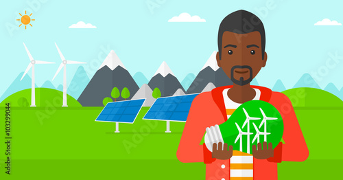 Man holding lightbulb with windmills inside.