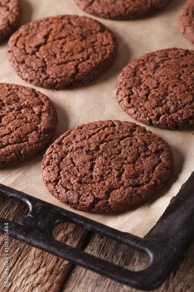 Fototapeta premium Freshly baked chocolate cookies on a baking sheet close-up. vertical