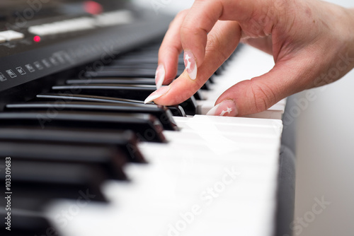 Woman hand playing a MIDI controller keyboard synthesizer close up