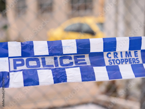 Blue and white Police tape cordoning off a area with a yellow car at a industrial area, Australia 2016
