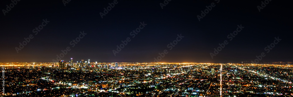 Naklejka premium Nocny widok panoramy z długiej ekspozycji na centrum Los Angeles i otaczający obszar metropolitalny z hollywoodzkich wzgórz