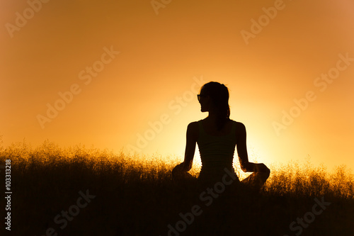 Young woman relaxing in a field. Meditation and serenity concept.
