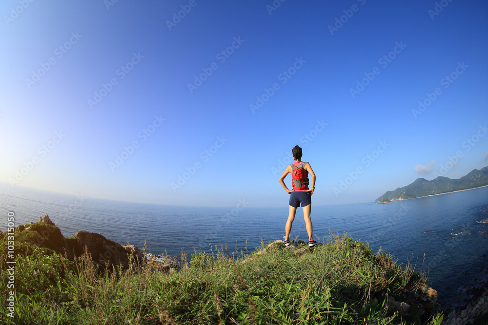 young woman hiker hiking on seaside mountain peak