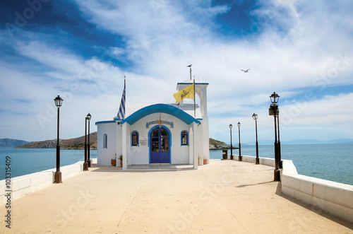 Perspective image of a Small greek orthodox chapel with some clouds above photo
