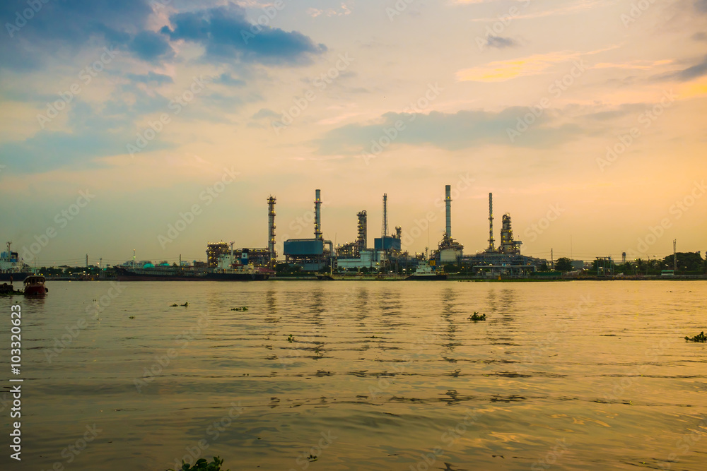 Fototapeta premium Silhouette of oil refinery factory over sunrise