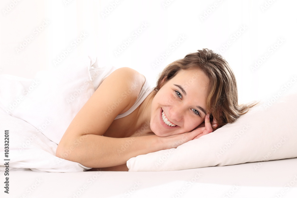 Junge Frau liegt glücklich im Bett
