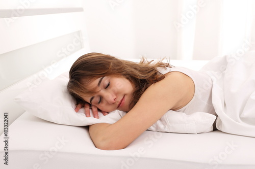 Junge Frau schläft im Bett mit Arm unter Kissen