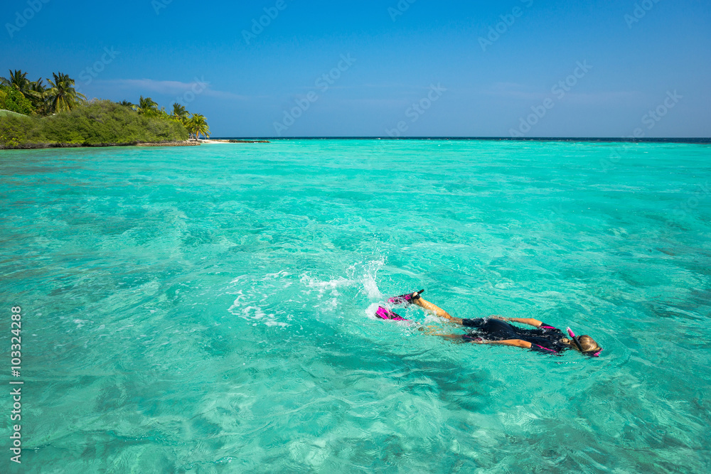 Woman snorkeling in clear tropical waters in front of exotic isl