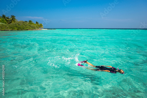 Woman snorkeling in clear tropical waters in front of exotic isl © gawriloff