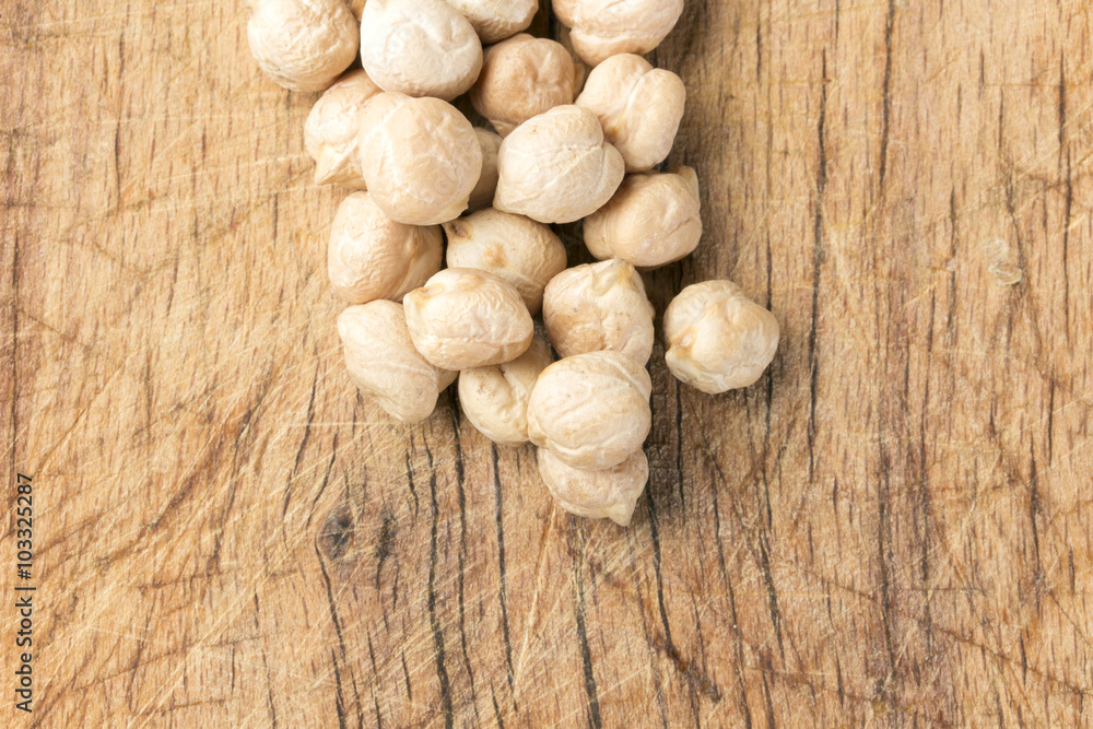 Uncooked chickpeas over wooden table close up.