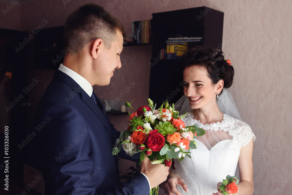 Handsome groom and beautiful bride posing with flowers in hotel Handsome groom and beautiful bride posing with flowers in hotel
