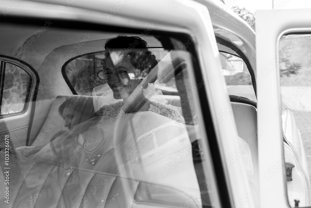 Beautiful brunette bride laughing in luxury white wedding car, w