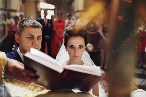 Spiritual beautiful bride and groom taking vows in church at Bib