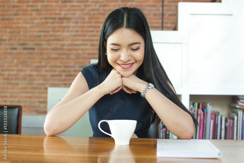 Asian woman looking at coffee cup and loving it in modern cafe Asian woman looking at coffee cup and loving it in modern cafe