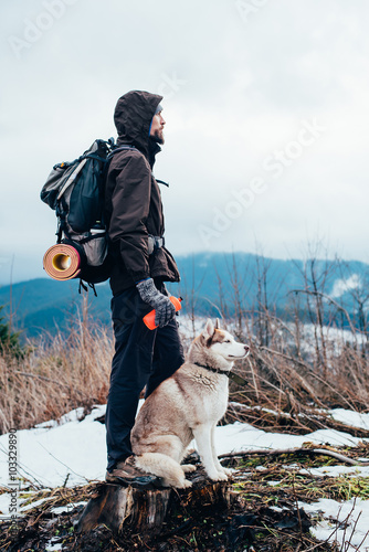 hiker with siberian husky dog looking at beautiful view in mountains