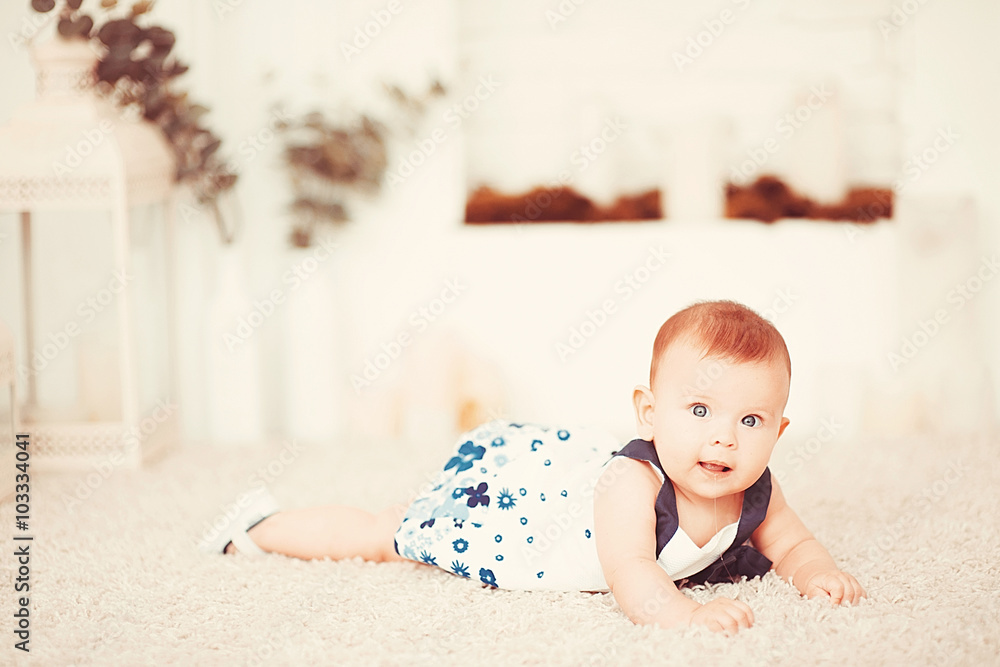 Beautiful little baby girl lies on a light carpet in the room Beautiful little baby girl lies on a light carpet in the room