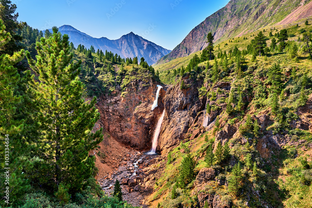 Waterfall in forest border in mountains