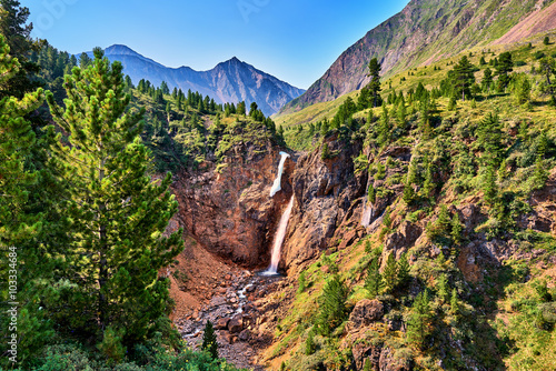 Waterfall in forest border in mountains