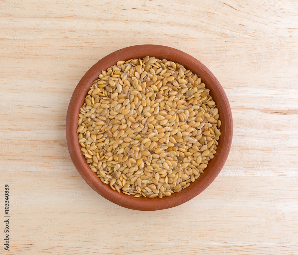 Bowl of organic golden flaxseed on a wood table top illuminated with natural light Bowl of organic golden flaxseed on a wood table top illuminated with natural light