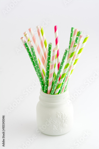 Colorful straws, striped and polka dots inside a white vase