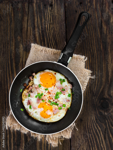 Fried eggs with ham and onion in pan