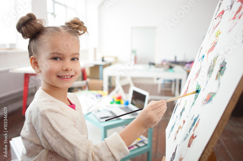 Cheerful little kid is painting with joy