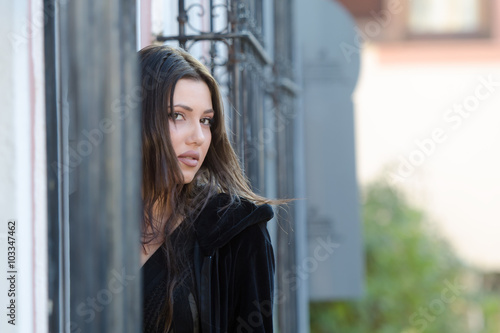 Pretty woman standing behind of a traditional window with iron bars, horizontal photo